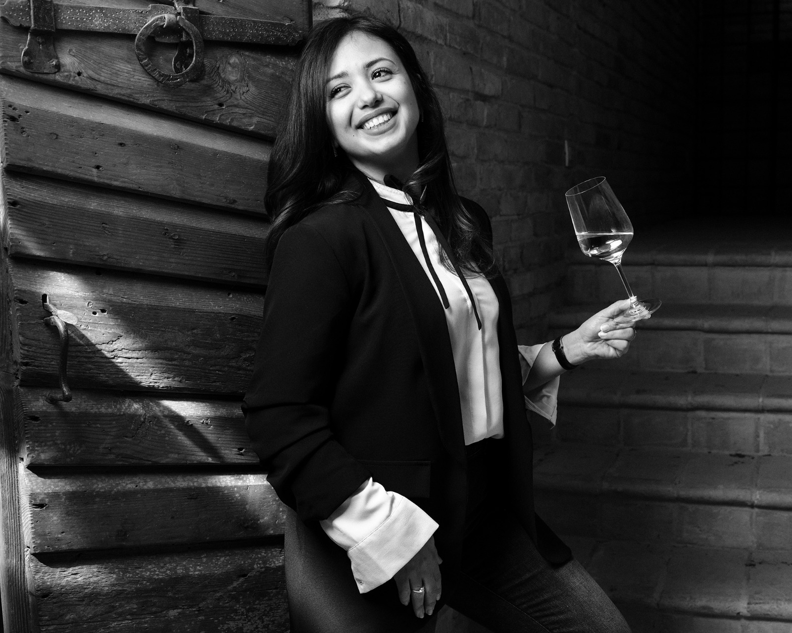 Luciana Dias, fondatrice di Gossip Wine, sorridente con un calice di vino bianco